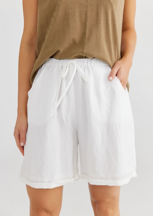 Dune Shorts - White, by Shanty Corp. • ELASTICATED WAISTBAND • NON-FUNCTIONAL FRONT DRAWSTRING •CUT AWAY FRONT POCKETS • MOCK SINGLE WELT BACK POCKET • ROLLED CUFF