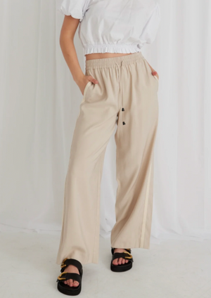 Townie Pant - Sand, by Stories be Told Details:  The Townie pants from Stories be Told are the ultimate pant that will be your new staple. These light weight, wide leg pants are so easy to throw on with a basic tank and sneakers.  - Elastic waistband with tie front  - Relaxed oversized fit  -Tape stripe side  -Hidden side pockets  -5cm deep hem  -Soft Viscose blend fabric