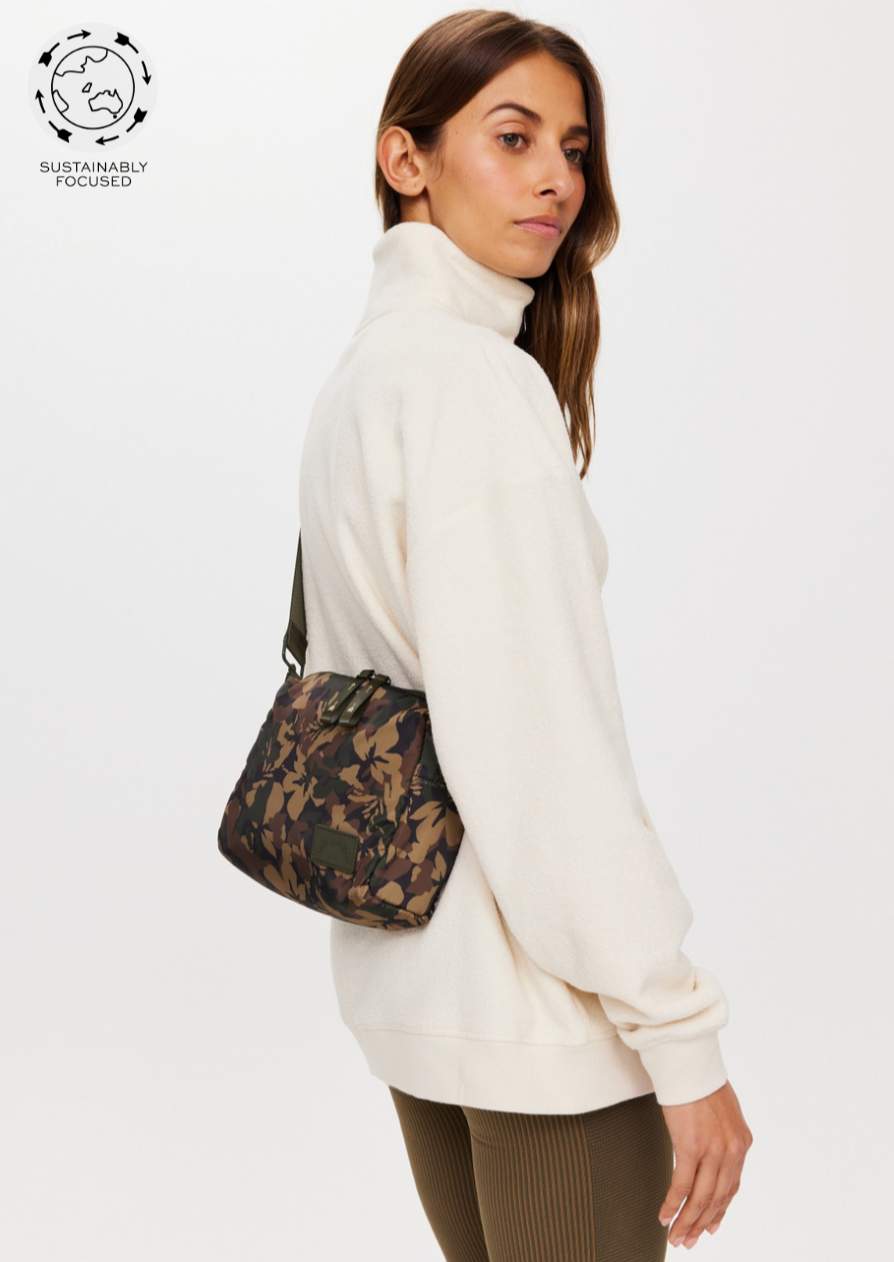 Basecamp Cosmic Crossbody Bag - Camo, by The Upside A compact carry all for all your necessities.  Recycled Polyester crossbody bag printed in our Basecamp camo Fully insulated and lined with internal pocket Chunky zipper with printed arrow at zip puller Adjustable olive green strap Please refer to studio images for accurate colour of garment
