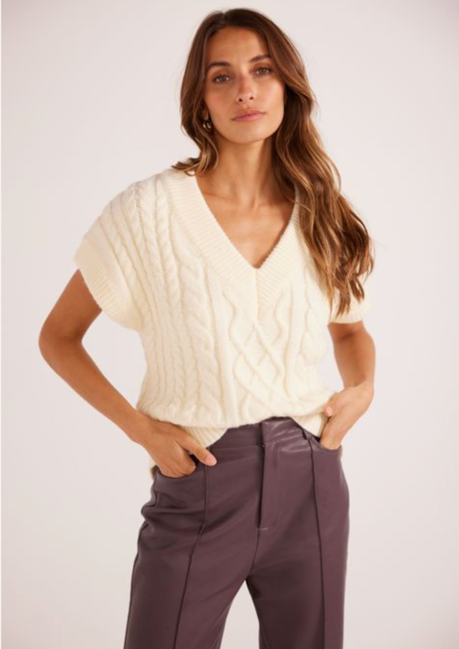<h3>Ester Knit Vest - Ivory, by Minkpink</h3> <p>The Esther Cable Knit Vest by MINKPINK features a relaxed fit, perfect to throw on for a cozy look. Wear yours with the new-in Yelena PU Pants to complete the look.- V neckline<br>- Cable knit design<br>- Upper arm coverage <br>- Ribbed hemline</p>