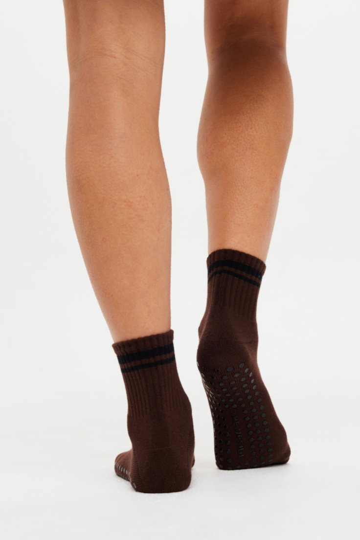 Brown grip socks with black stripes 
worn by person on a white background
