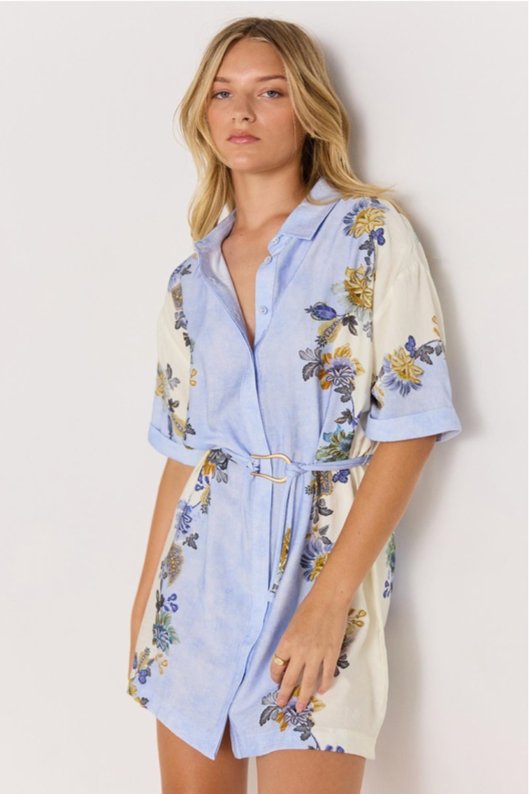 Lucia Mini Shirt Dress - Blue &amp; Cream Floral, by MInkpink

The Lucia Blue &amp; Cream Floral Mini Shirt Dress is a breezy, feminine style perfect for warm days. Featuring a soft watercolour blue and cream base with vibrant floral prints, it’s designed with a relaxed fit, button-down front, and a removable belt to cinch the waist. Rolled short sleeves add a casual touch, making it ideal for both beach strolls and brunch dates.