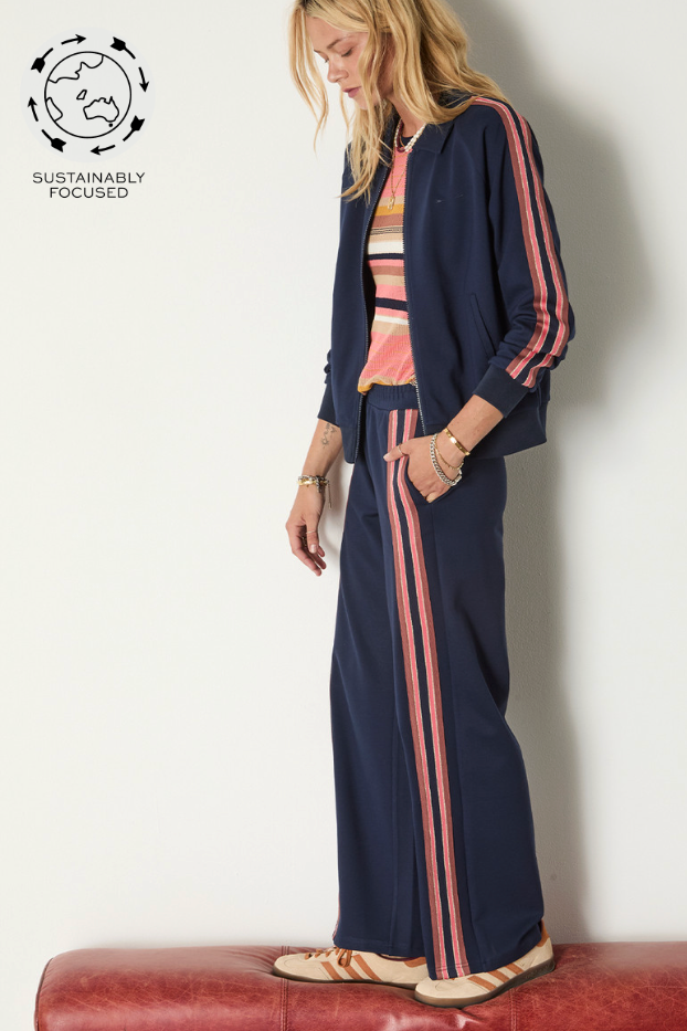 Ananda Wide Leg Cody Pant - Navy, by The Upside

A navy wide-leg pant finished with textured stripes in pink, gold and navy

Wide leg pant in navy
Elasticated waistband
Textured knitted stripe tape down side seam in navy, gold and pink
Side seam pockets
Embroidered arrow at back
Lenzing viscose soft suiting fabrication
Please refer to studio images for accurate colour of garment