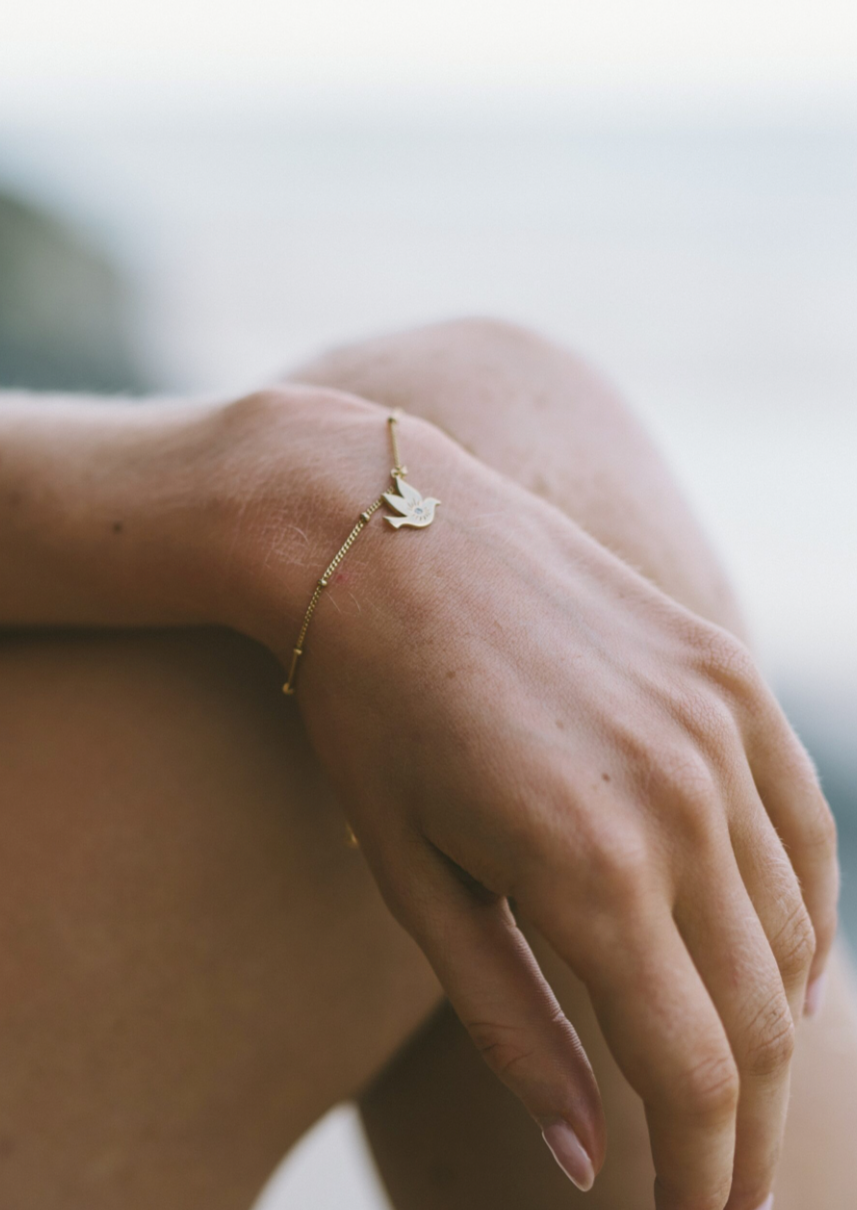 Paloma Bracelet in Gold | Love Lunamei        Stack It                New              Adjustable  Peace and Love  Our Peace Bird Collection has been designed to bring the wearer a sense of calm and complete harmony while reflecting on the tumultuous times we have recently endured. Featuring sparkling cubic zirconia, the delicately etched Peace Bird is a symbol of love and renewal of life.